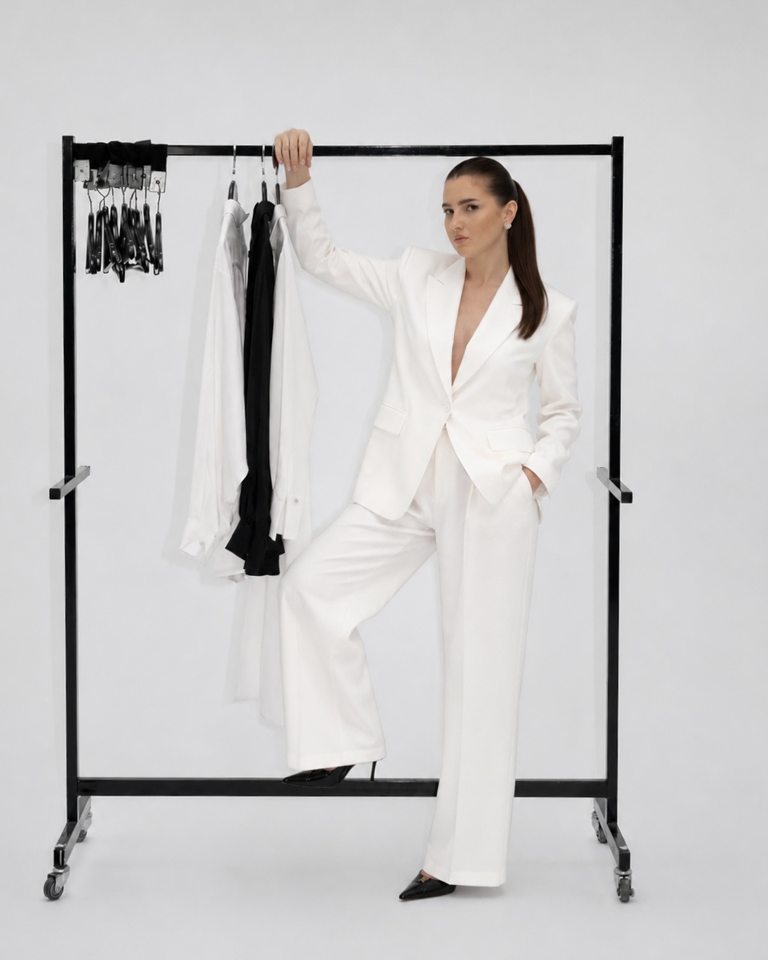 Patricia standing beside a clothing rack in a white suit